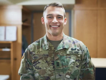 A smiling person in u.s. army camouflage uniform indoors.