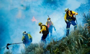 Firefighters battling a wildfire on a hillside.